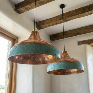 Two copper pendant lights with turquoise interior hanging from wooden beams.
