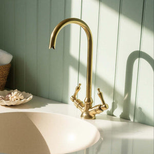 Gold faucet on a sink with a light green wall in the background