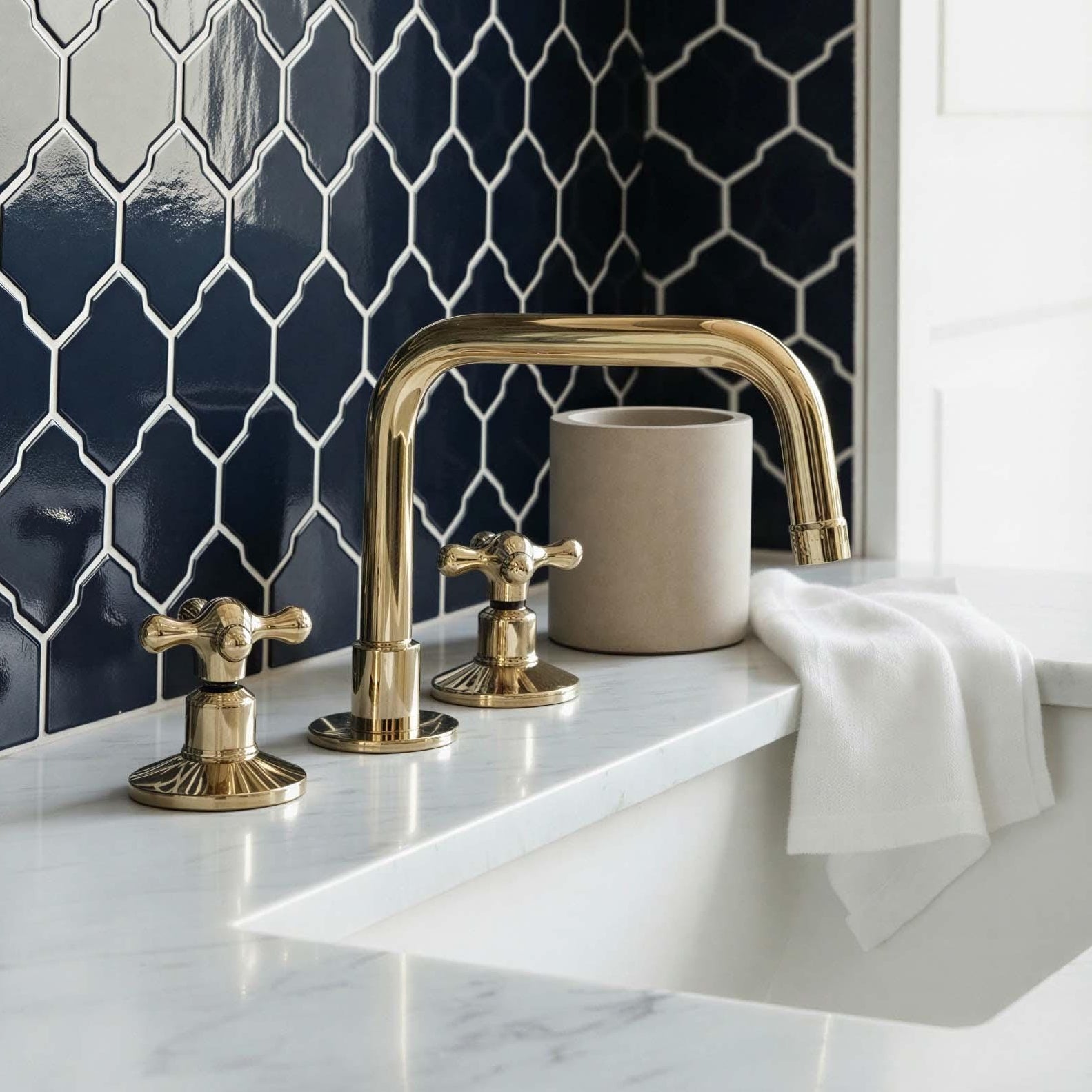 Gold faucet and handles on a marble countertop with navy tiled wall