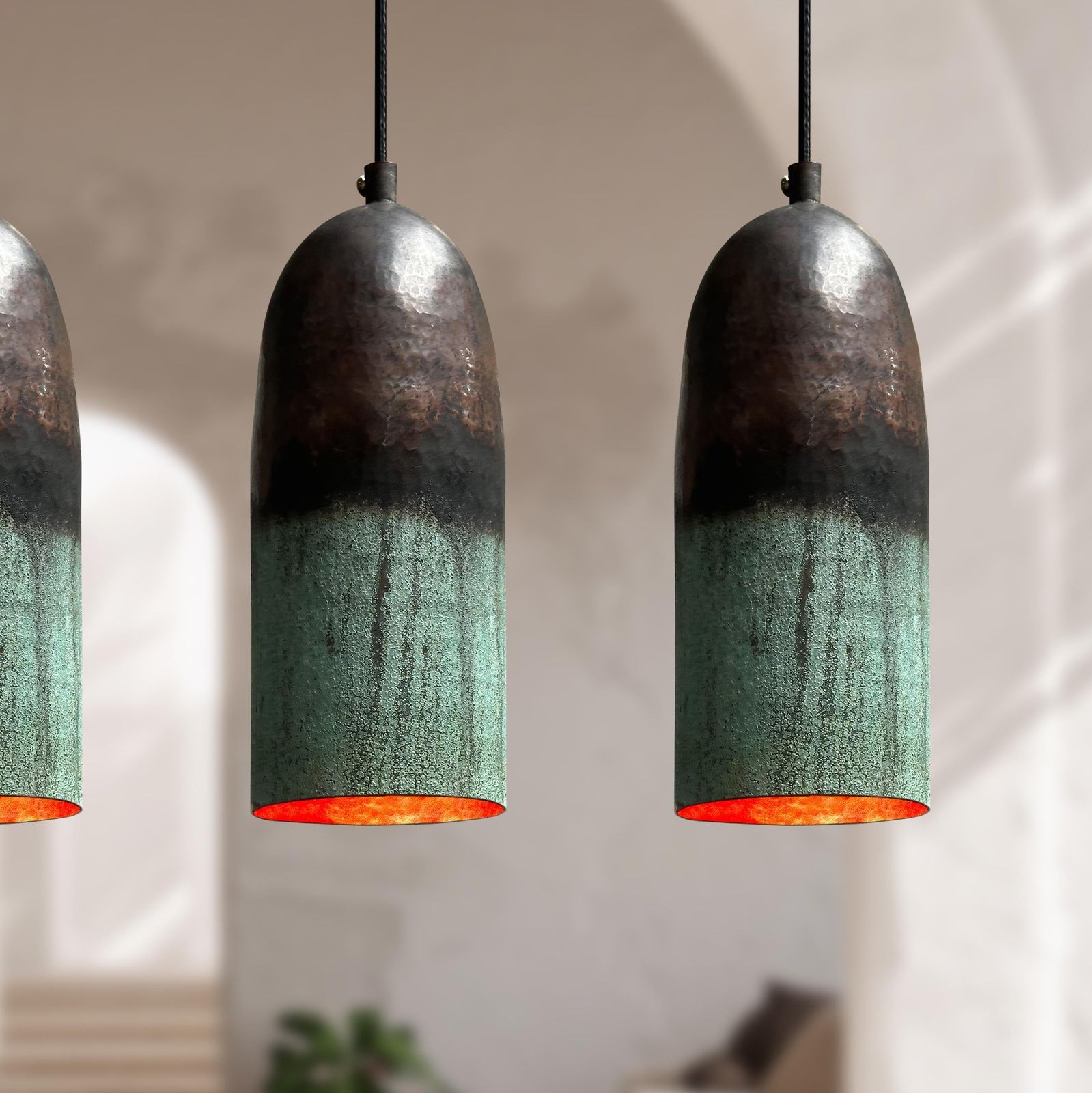 Three pendant lights with green and black shades hanging against a neutral background.
