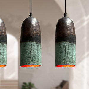 Three pendant lights with green and black shades hanging against a neutral background.