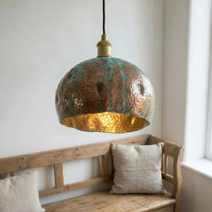 Copper pendant light hanging above a wooden bench with pillows in a room.