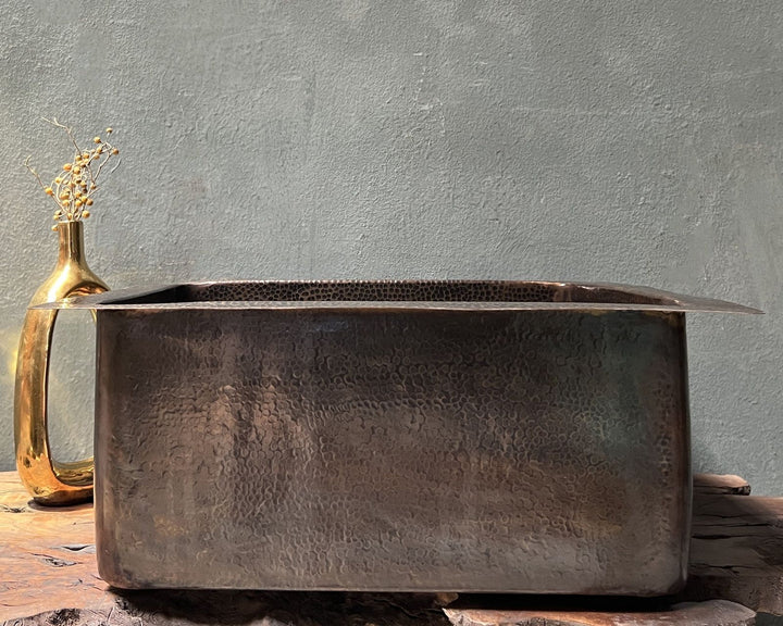 Rustic metal basin on a wooden surface with a textured gray wall background