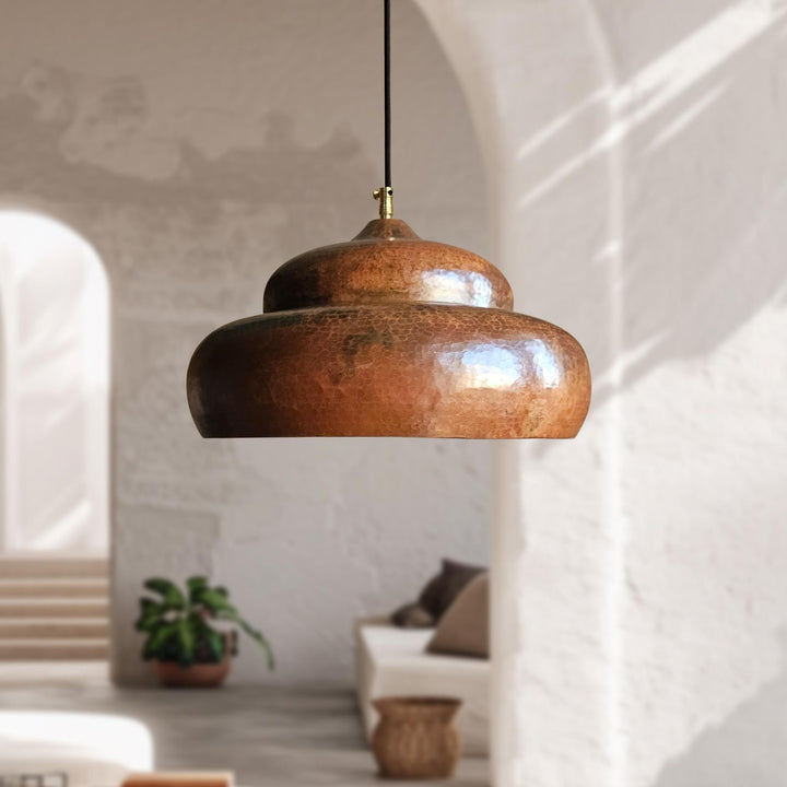 handmade copper pendant light hanging in a room with a neutral color palette