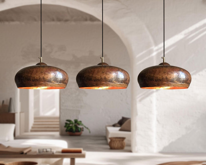 Three hanging copper pendant lights in a modern interior setting.