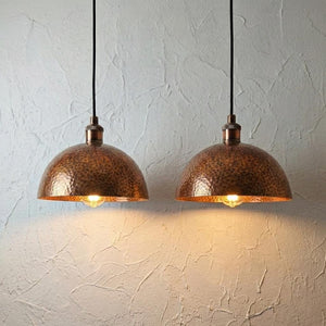 Two copper pendant lights hanging against a textured white wall.