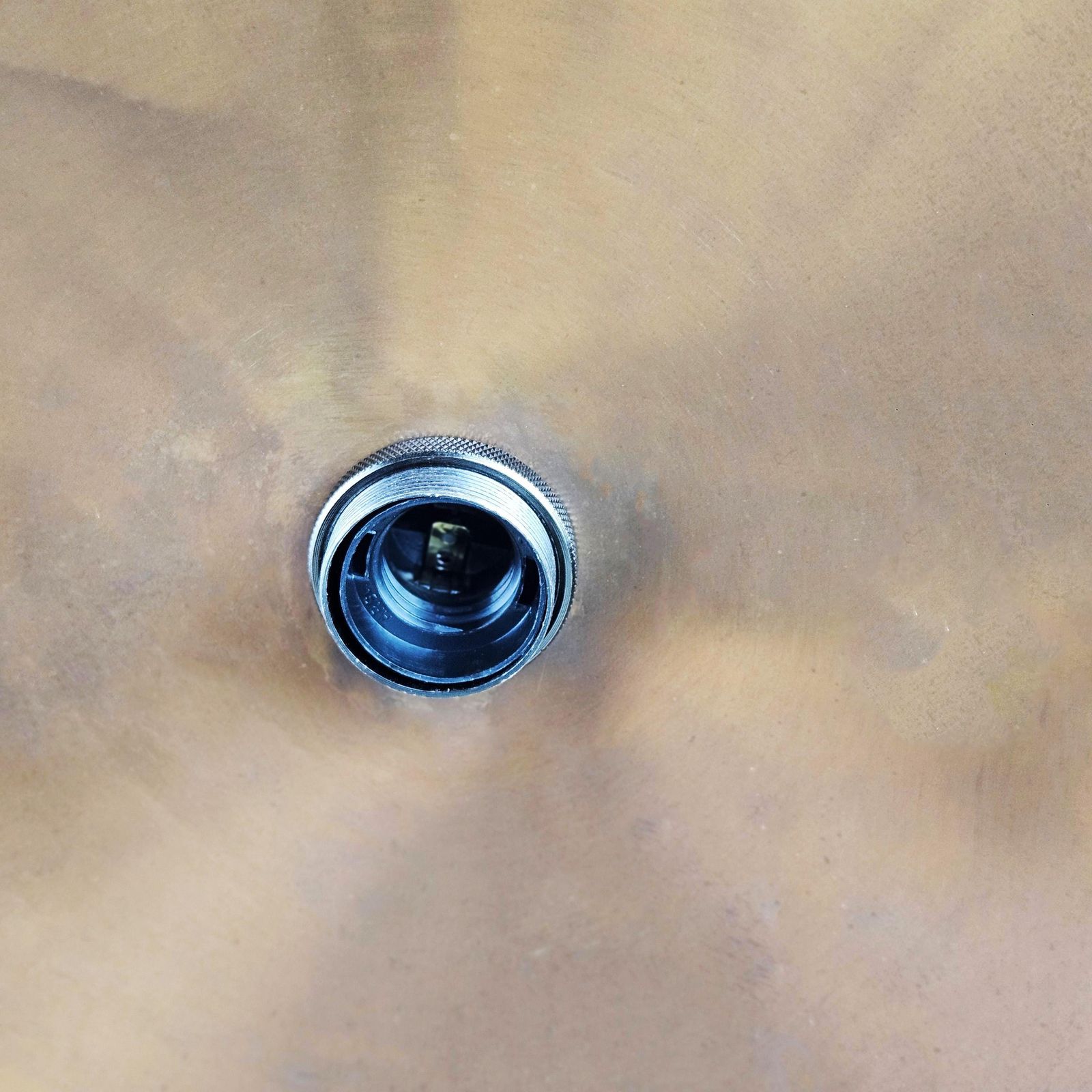 Metal drain plug on a beige metal surface