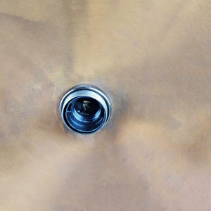 Metal drain plug on a beige metal surface