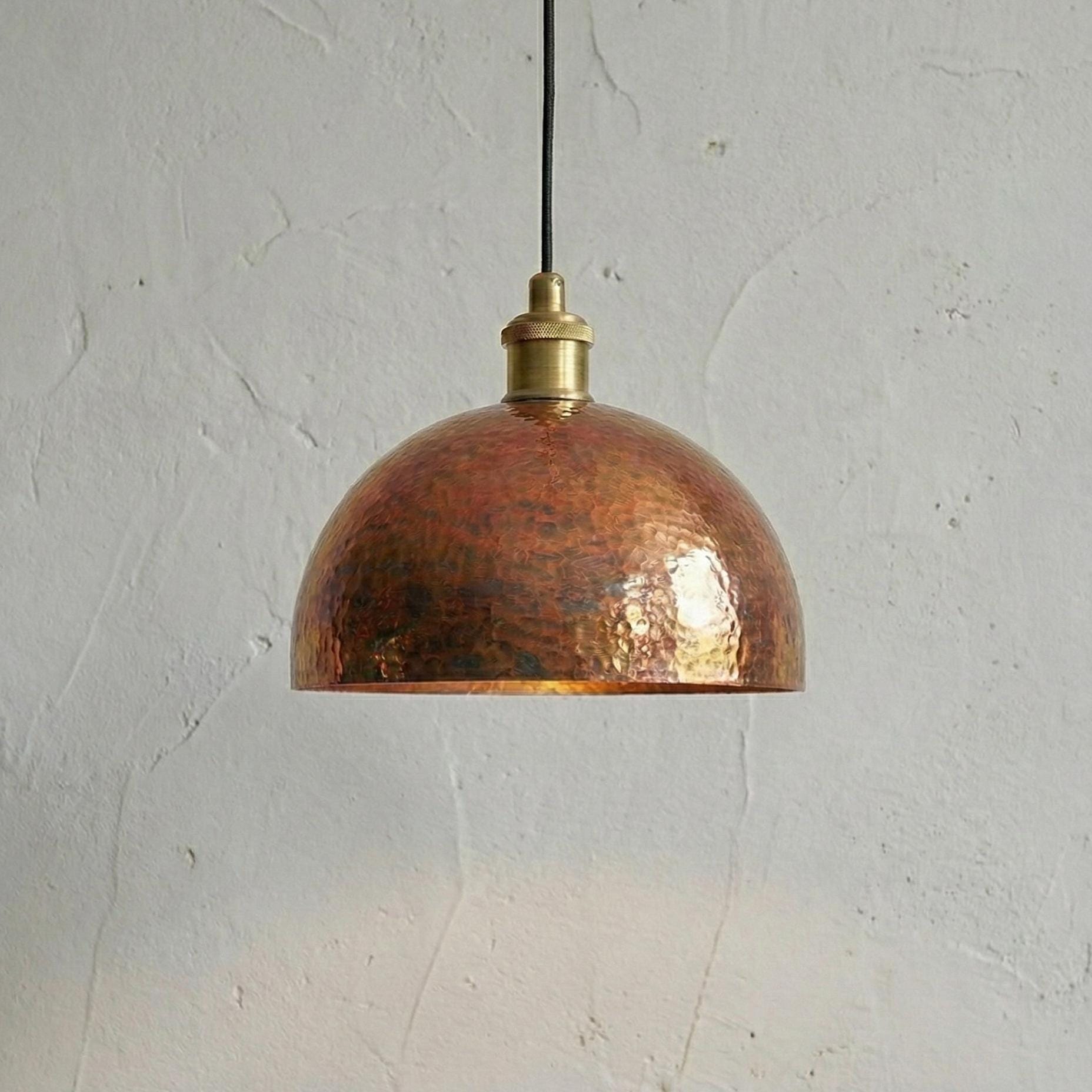 Copper pendant light with brass fitting on a white wall