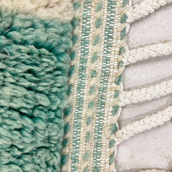 Hand-finished fringe on an aqua and ivory wool rug