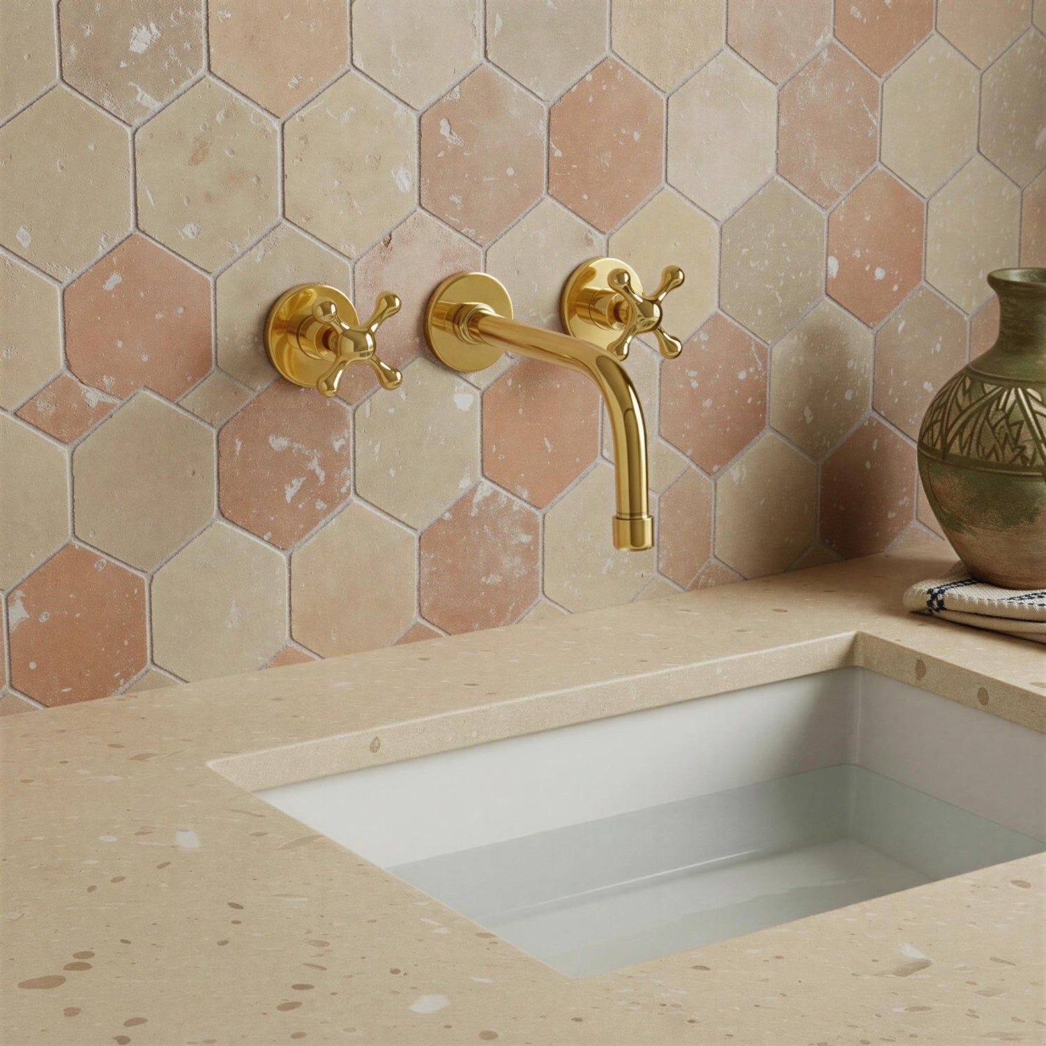 Gold faucet on a tiled wall with a sink below