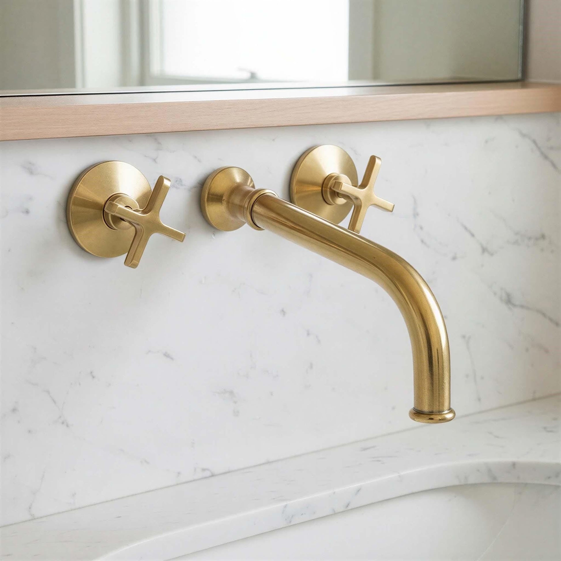 Gold faucet and handles on a marble bathroom wall