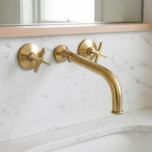 Gold faucet and handles on a marble bathroom wall