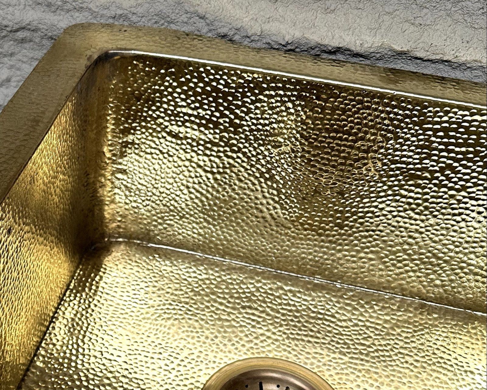 Gold metallic sink with textured surface on a gray concrete background
