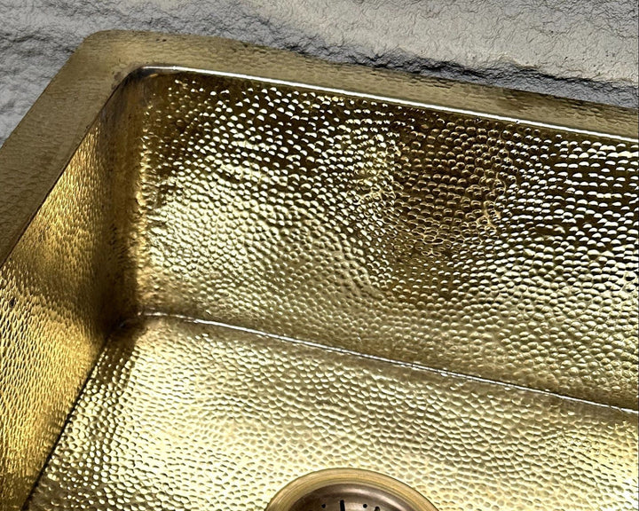 Gold metallic sink with textured surface on a gray concrete background