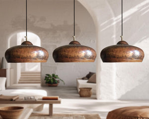 Three copper pendant lights hanging in a room with a neutral color palette.