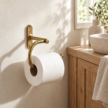 Curved solid brass toilet paper holder in a warm neutral farmhouse bathroom