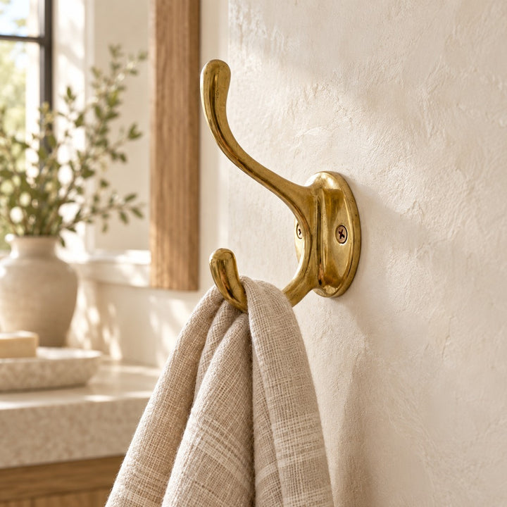 Decorative scroll solid brass wall hook with linen towel in a warm bathroom