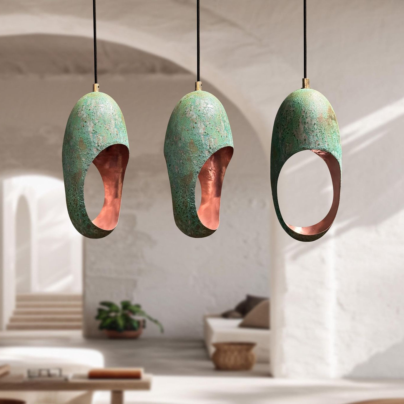 Three green and copper pendant lights hanging in a room with a blurred background