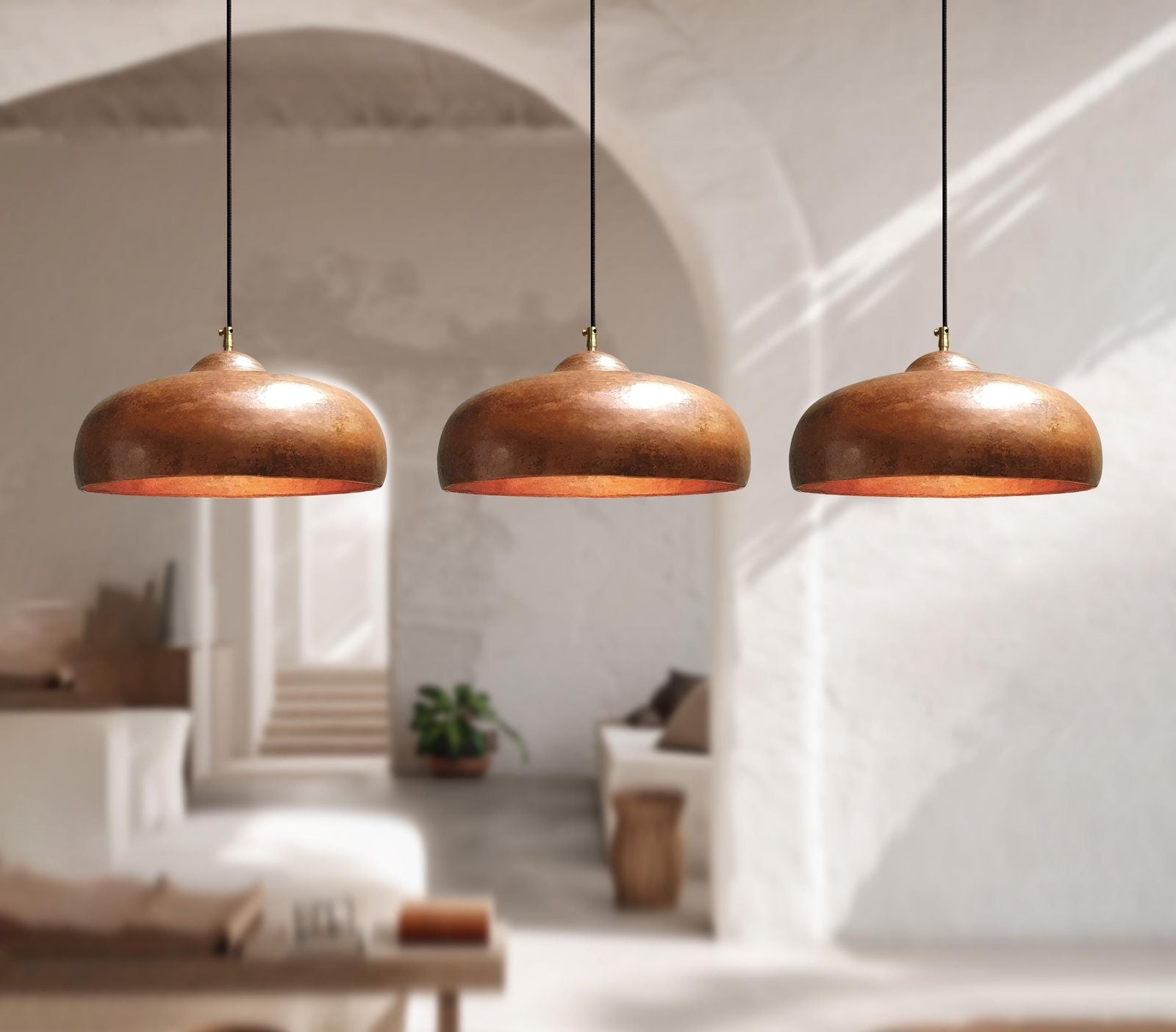 Three solid copper pendant lights hanging in a modern interior setting.