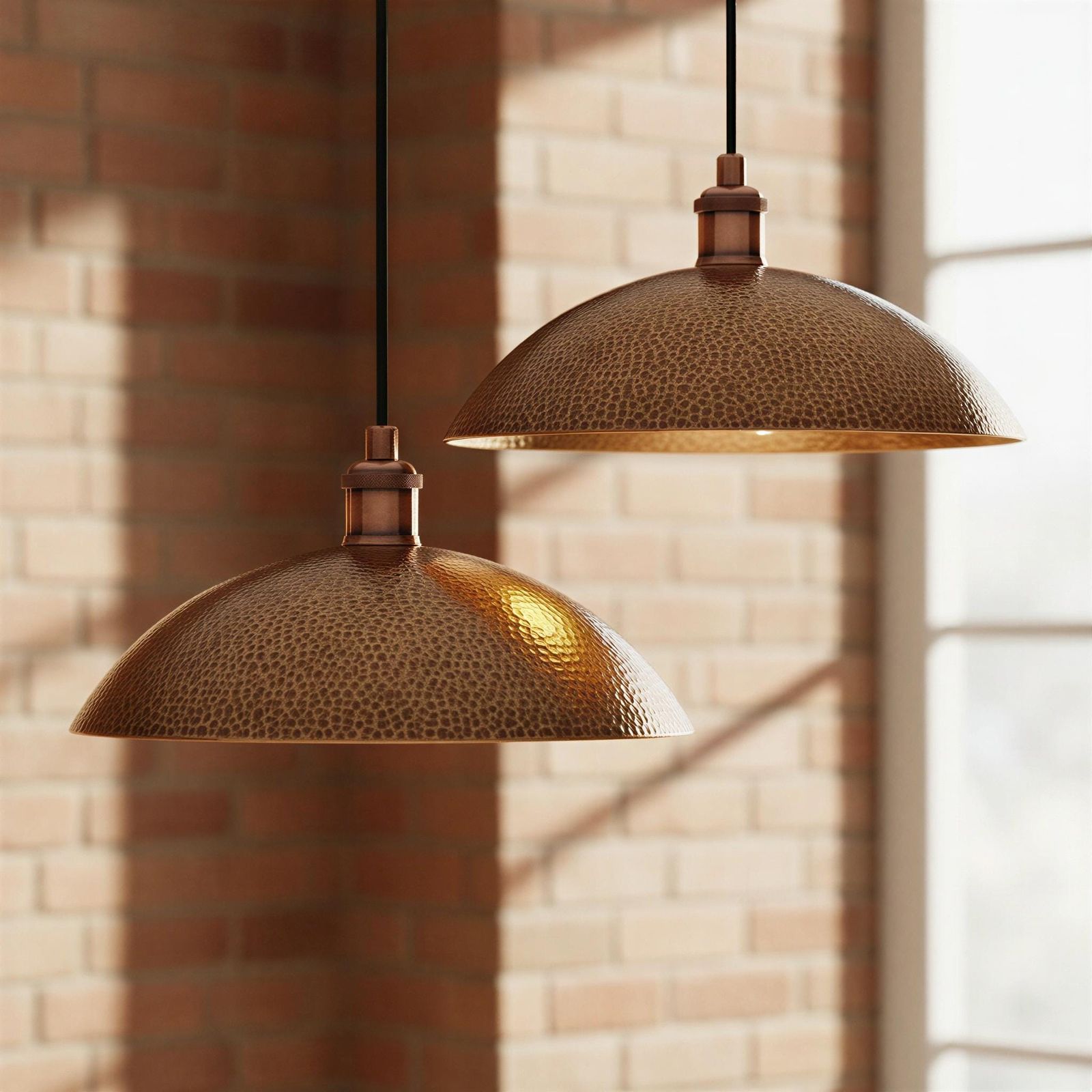 Two bronze pendant lights hanging against a brick wall.