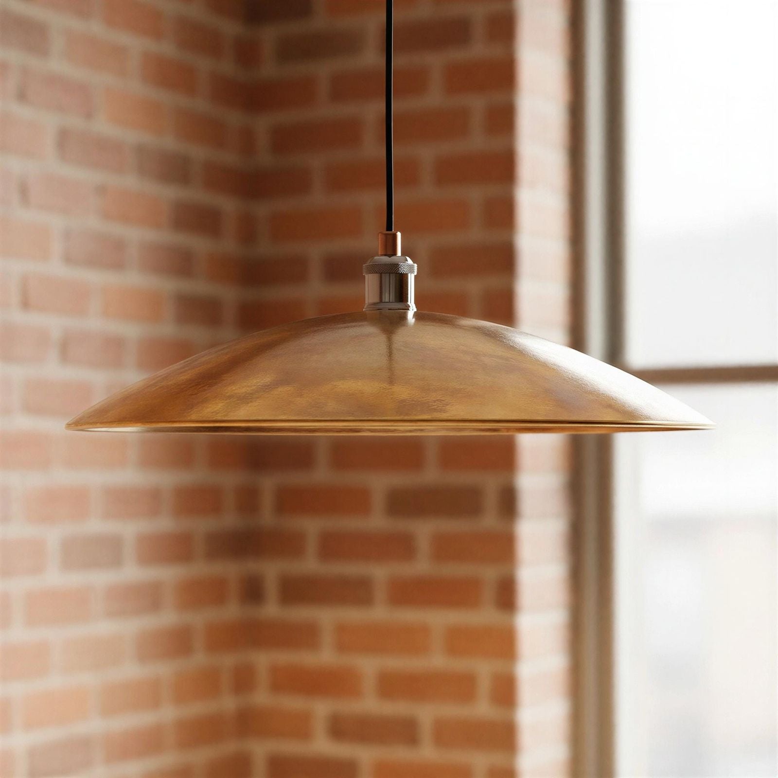 Gold pendant light hanging against a brick wall