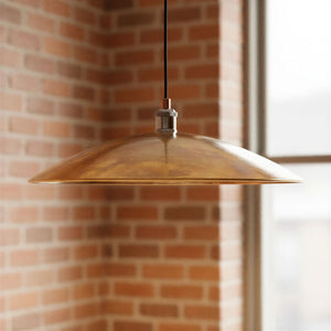 Gold pendant light hanging against a brick wall