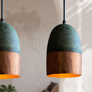 Two pendant lights with green top and copper bottom on a blurred background