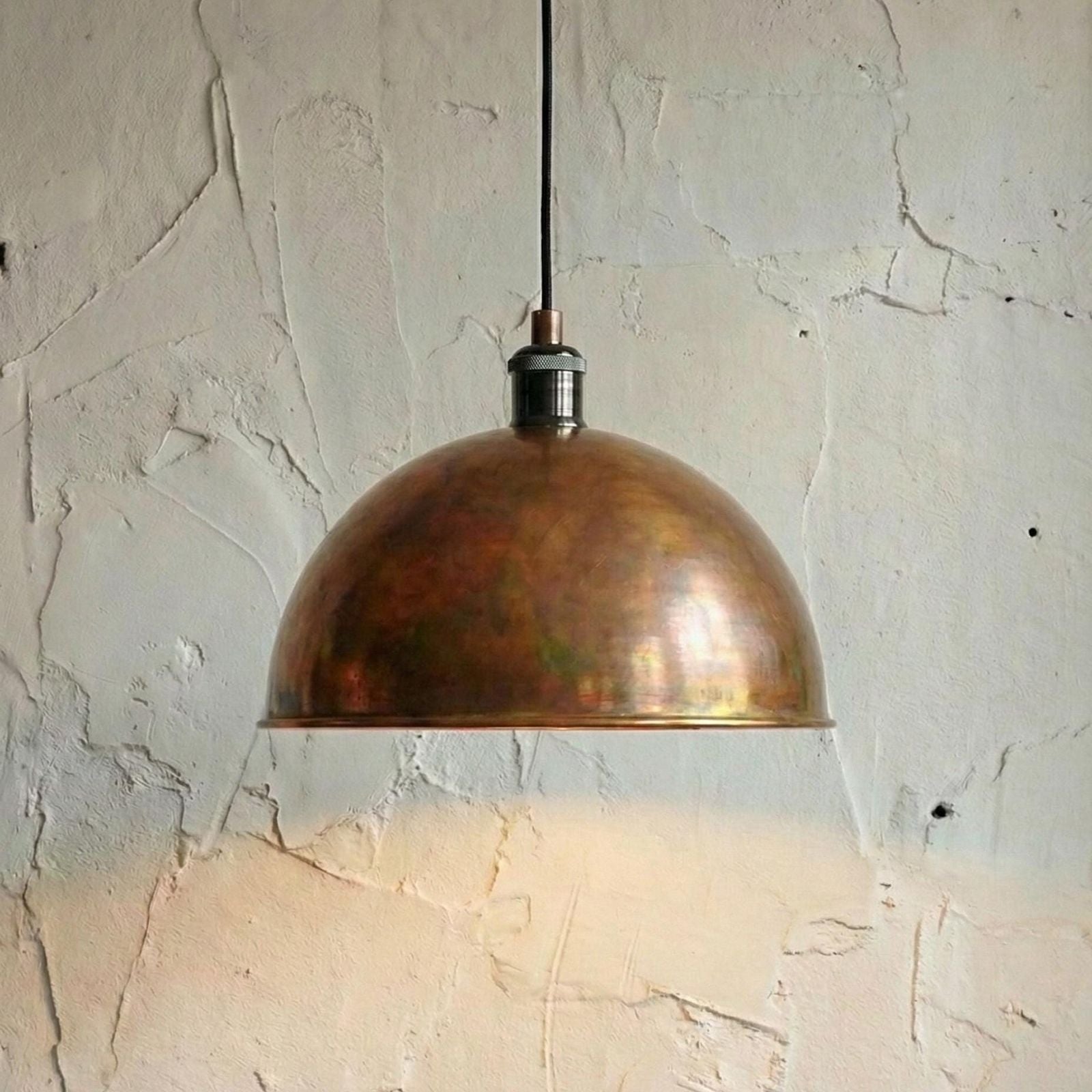 Bronze pendant light hanging against a textured wall.