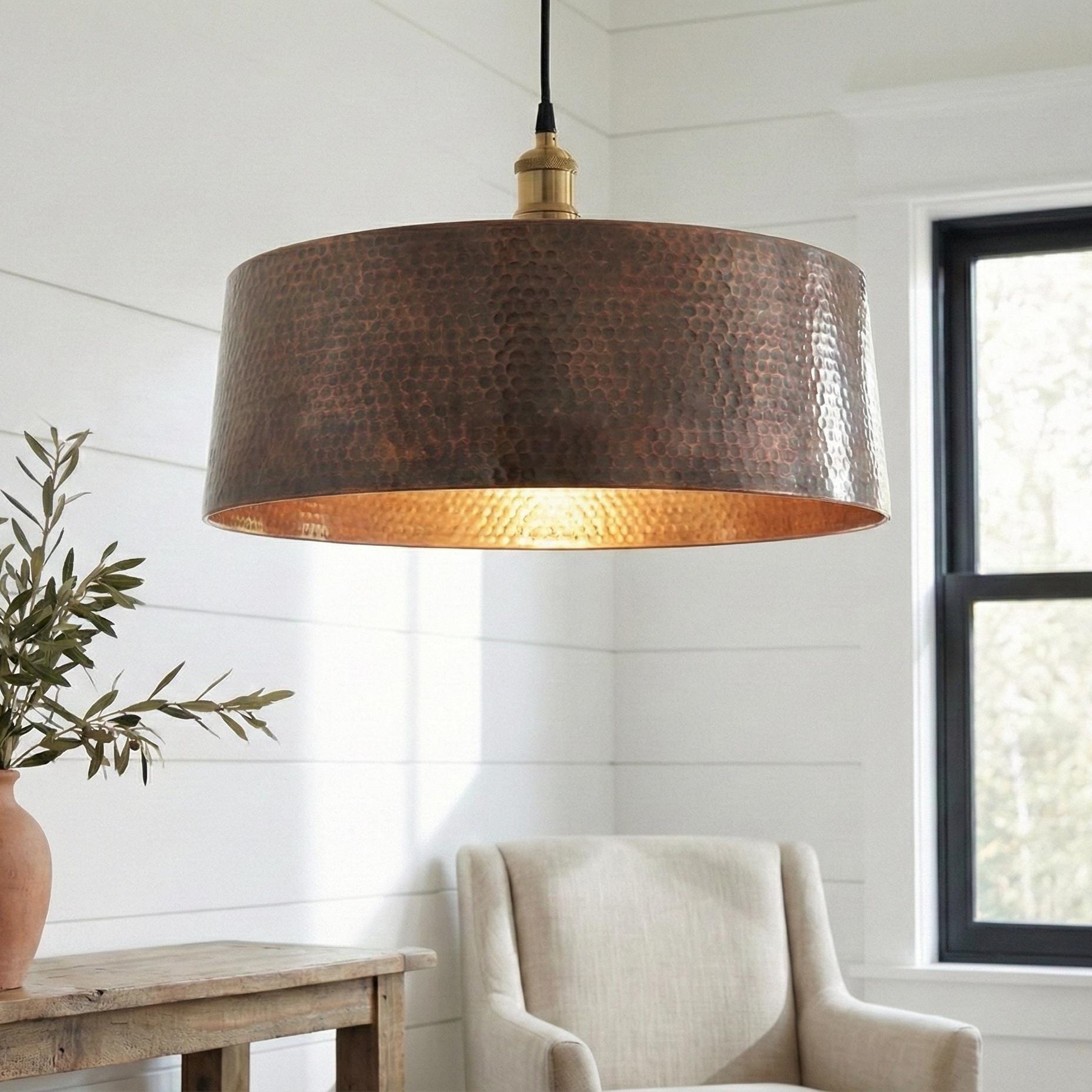 Hanging lamp with a textured brown shade in a room with a chair and plant.