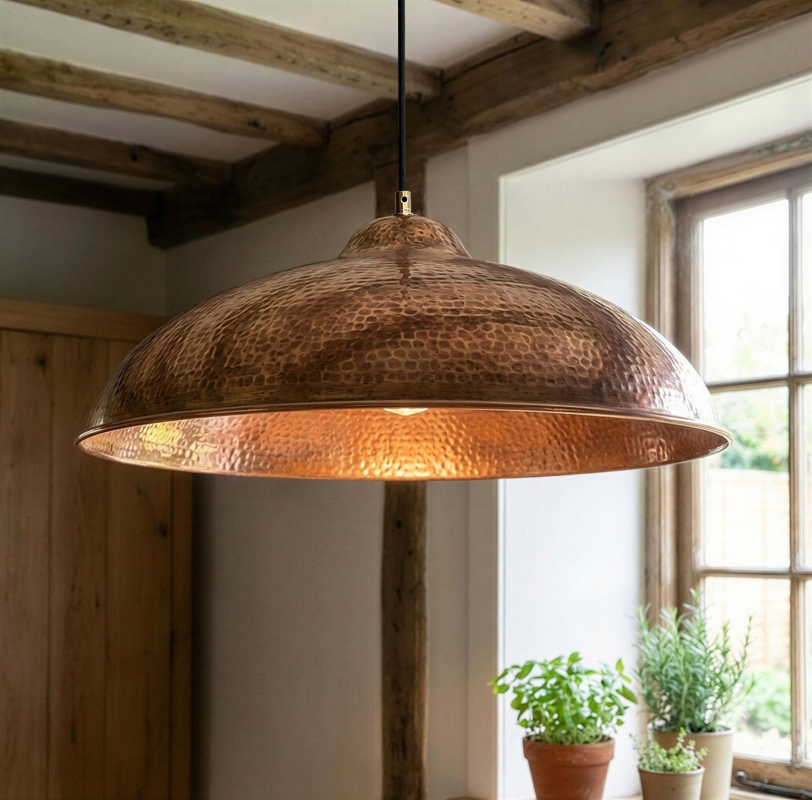 Copper pendant light hanging in a room with wooden beams and windows.