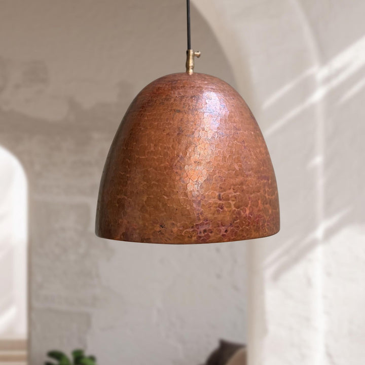Copper pendant light hanging against a neutral wall
