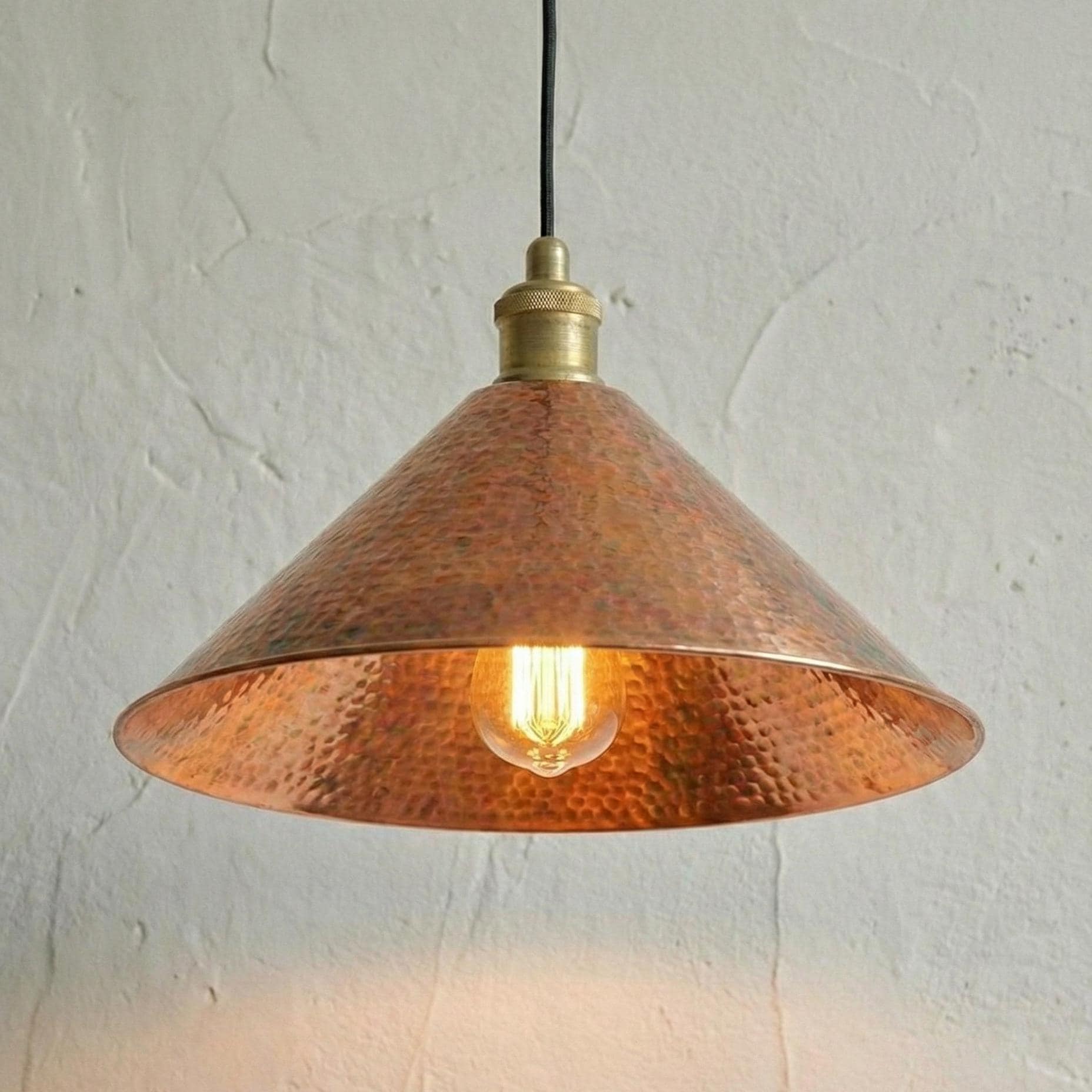 Copper pendant light with a textured shade on a white wall background