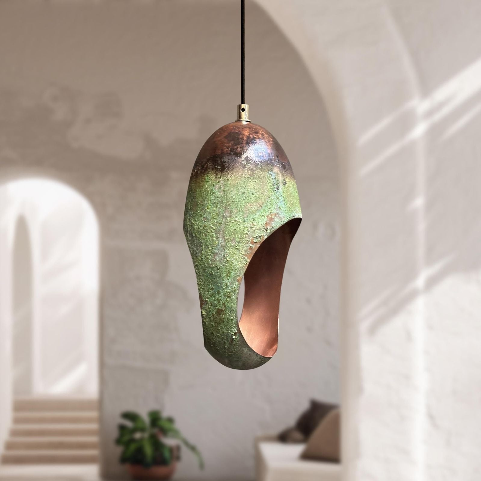 Green copper pendant light hanging in a room with a neutral color palette.