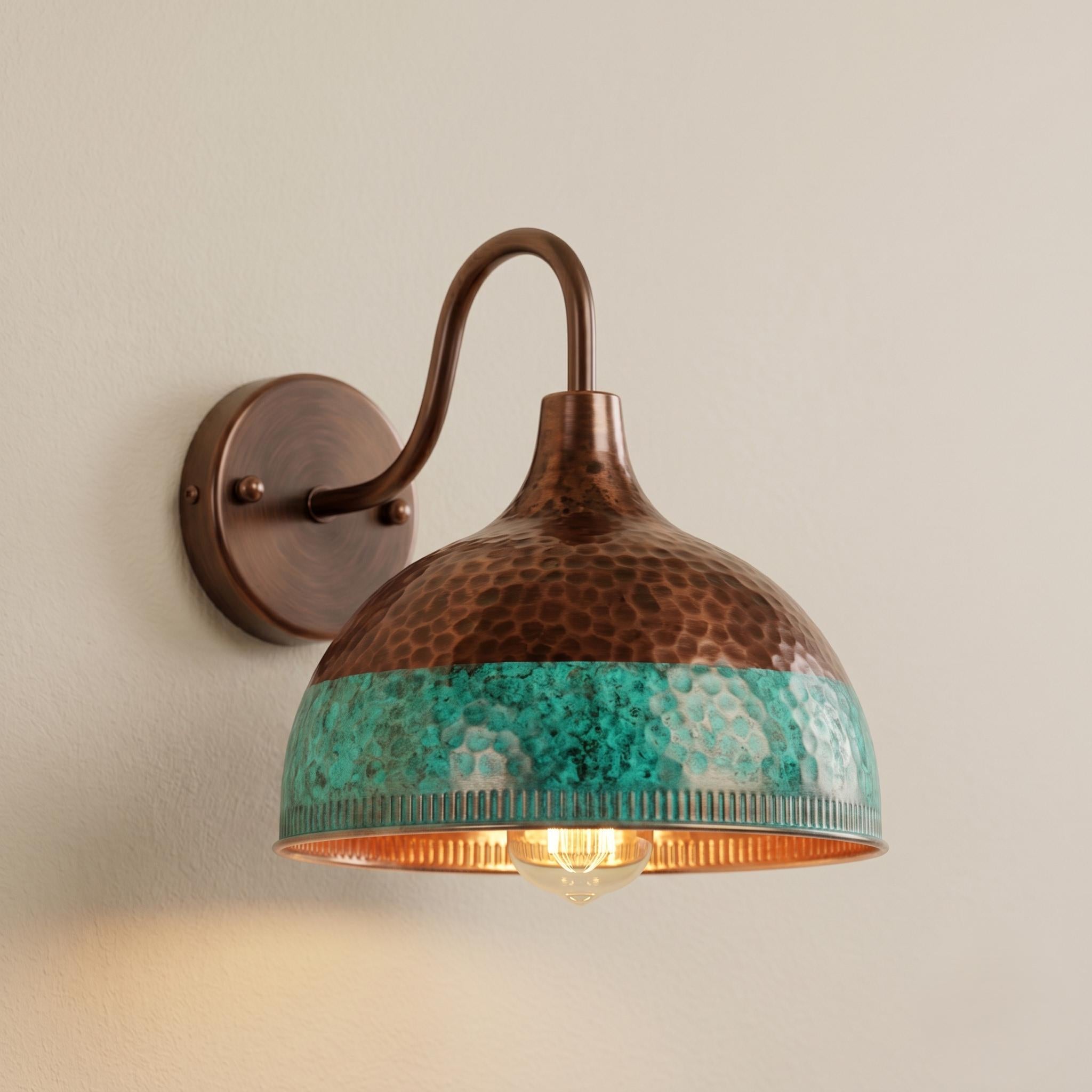 A rustic wall-mounted sconce with a hammered copper dome shade featuring a turquoise blue-green band around the middle, mounted on a beige wall.