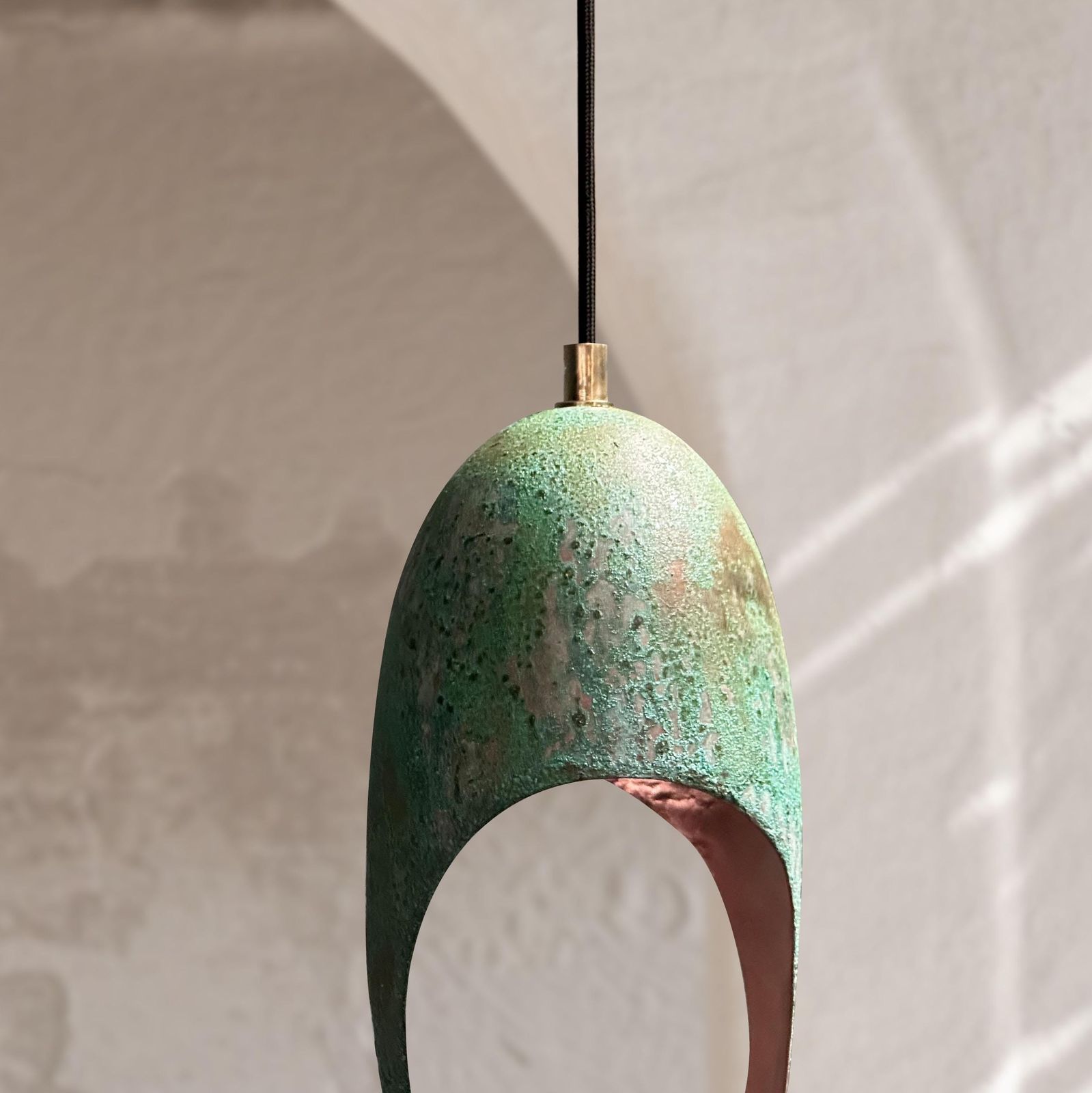 Green ceramic pendant light against a neutral background