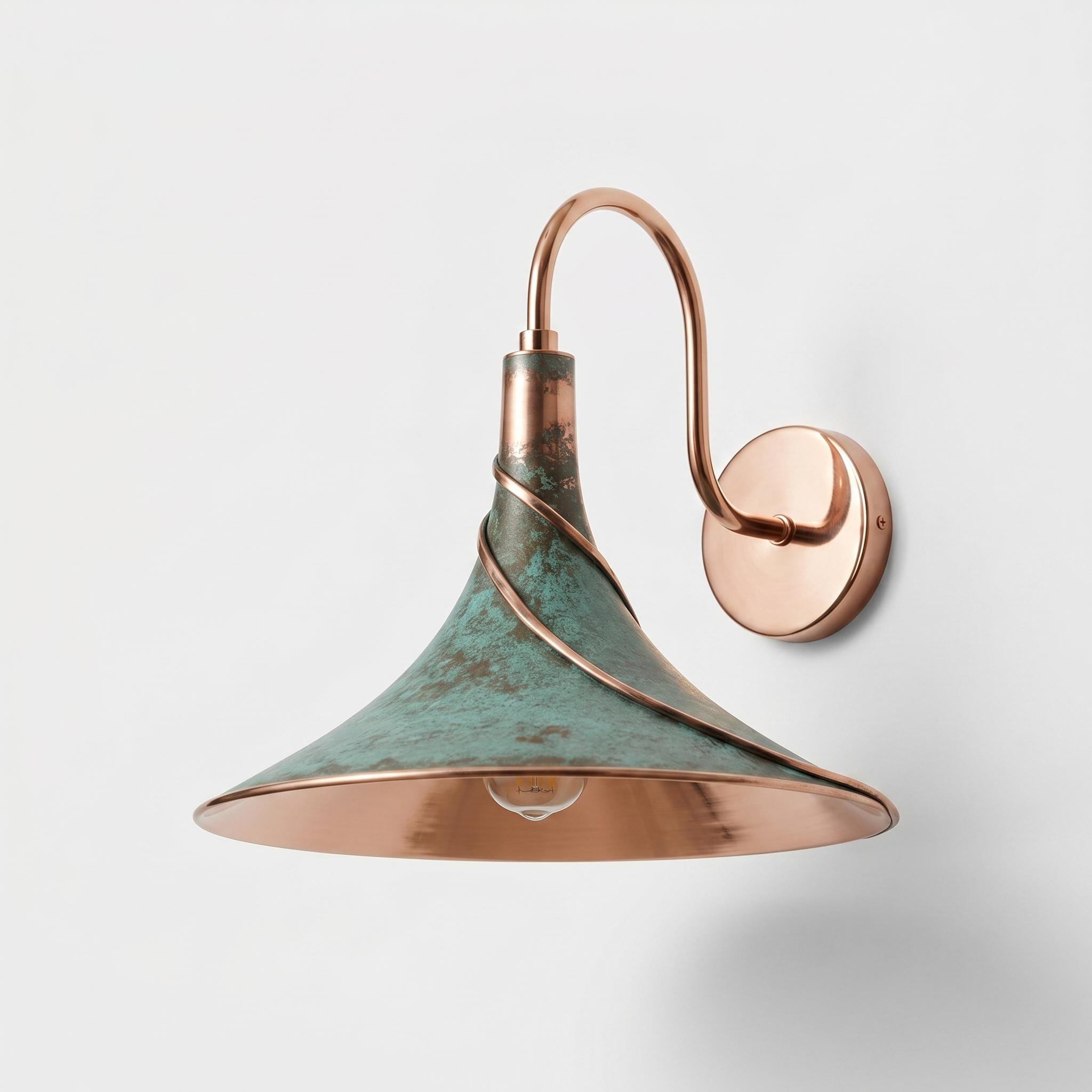 A wall-mounted sconce with a copper-toned metal arm and a conical shade featuring a distressed green patina finish and a polished copper interior.