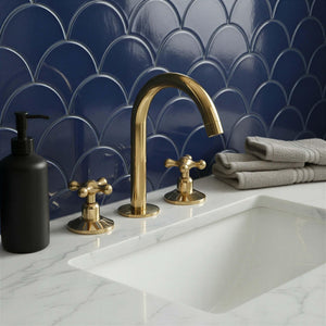 Bathroom sink with gold faucet and black soap dispenser against a blue tiled wall.