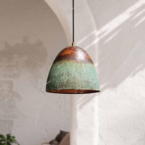 Pendant light with a textured green and copper finish hanging against a white wall.