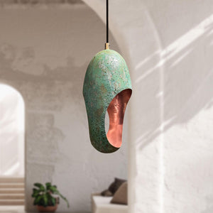 Decorative pendant light with green and copper finish hanging in a room.