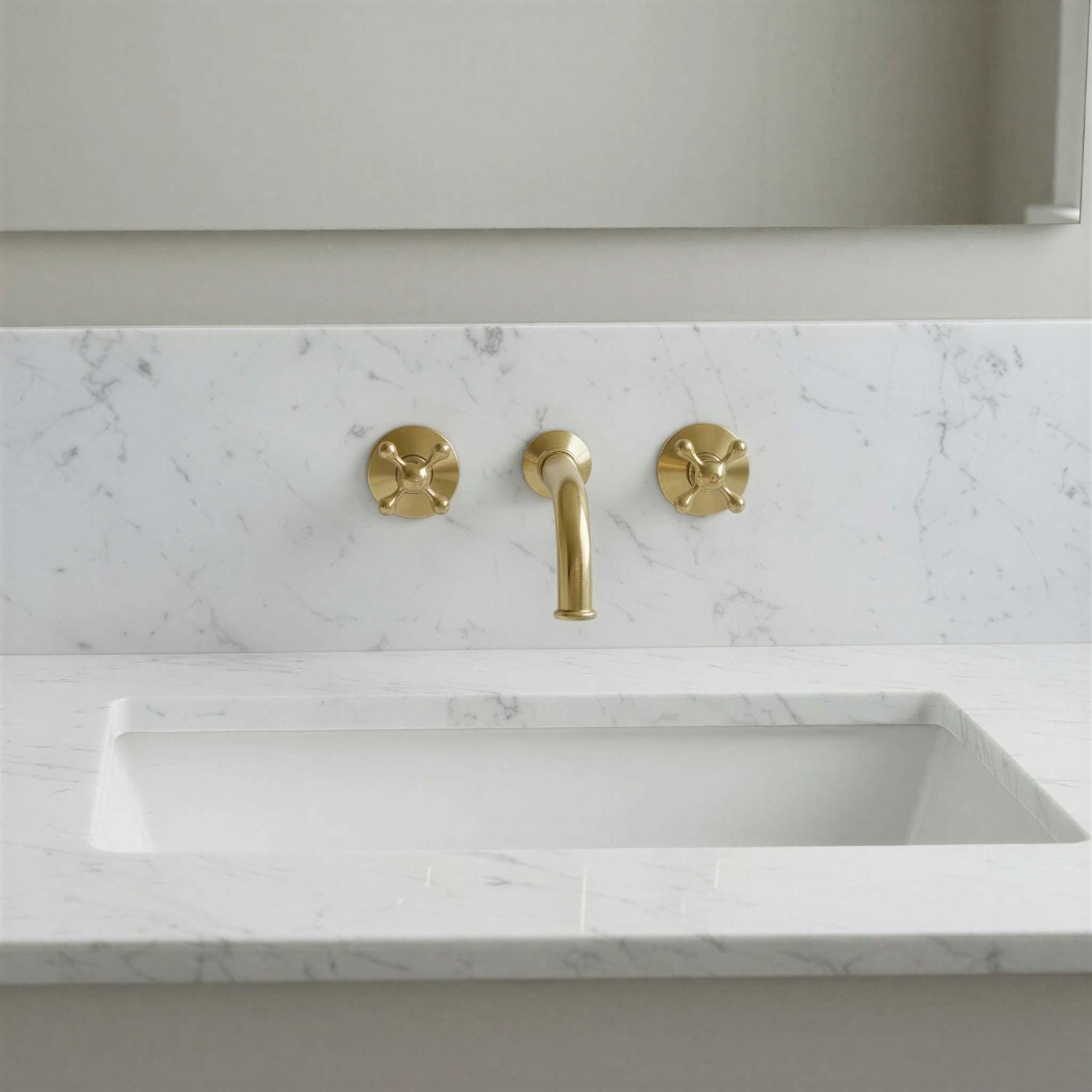 Marble sink with gold faucet and handles in a bathroom setting