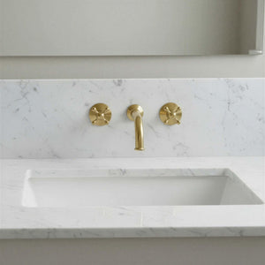 Marble sink with gold faucet and handles in a bathroom setting