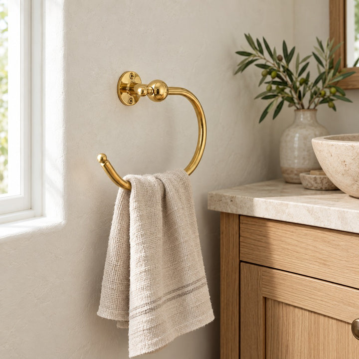 Round solid brass towel ring with linen hand towel in a warm neutral bathroom