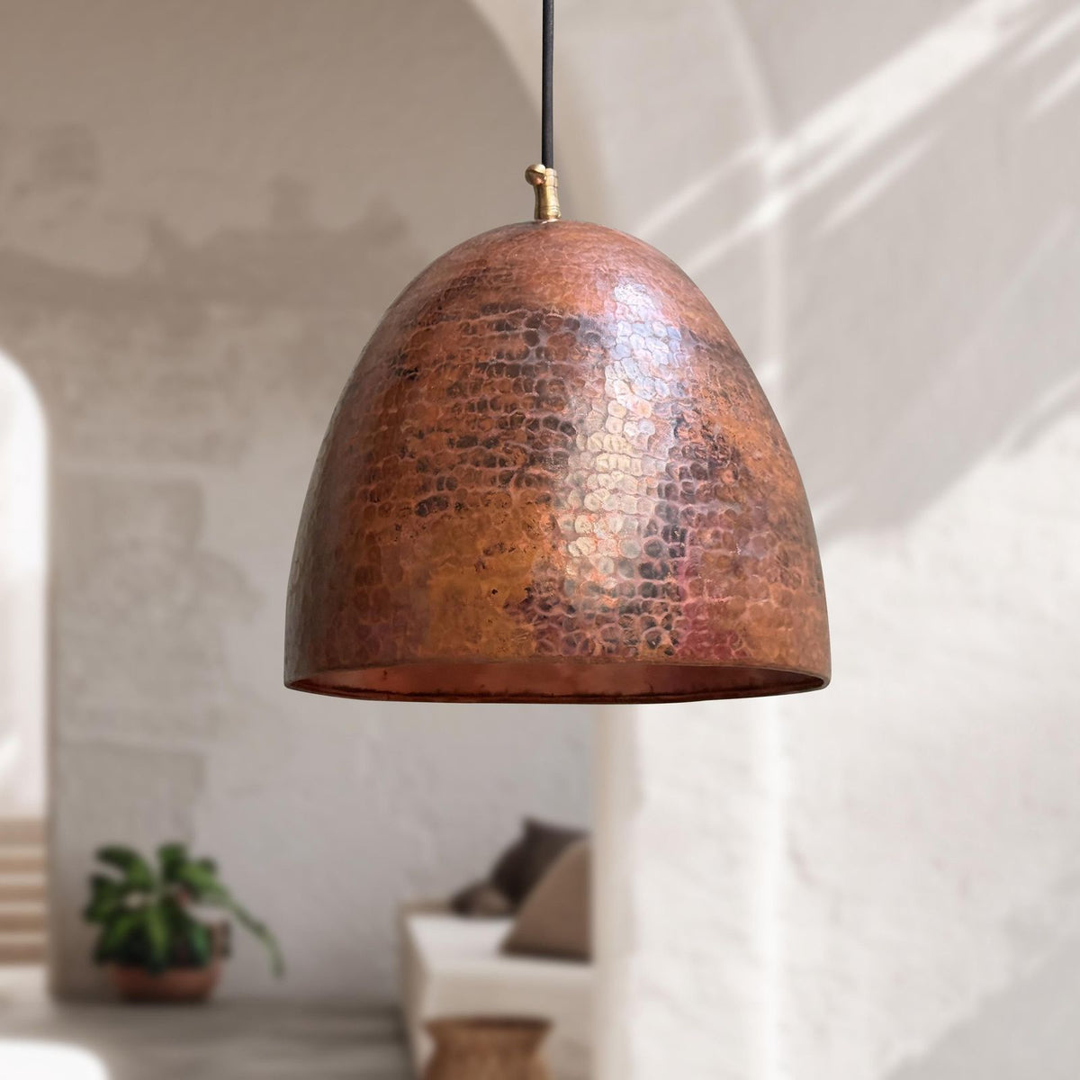 Copper pendant light hanging in a room with a blurred background