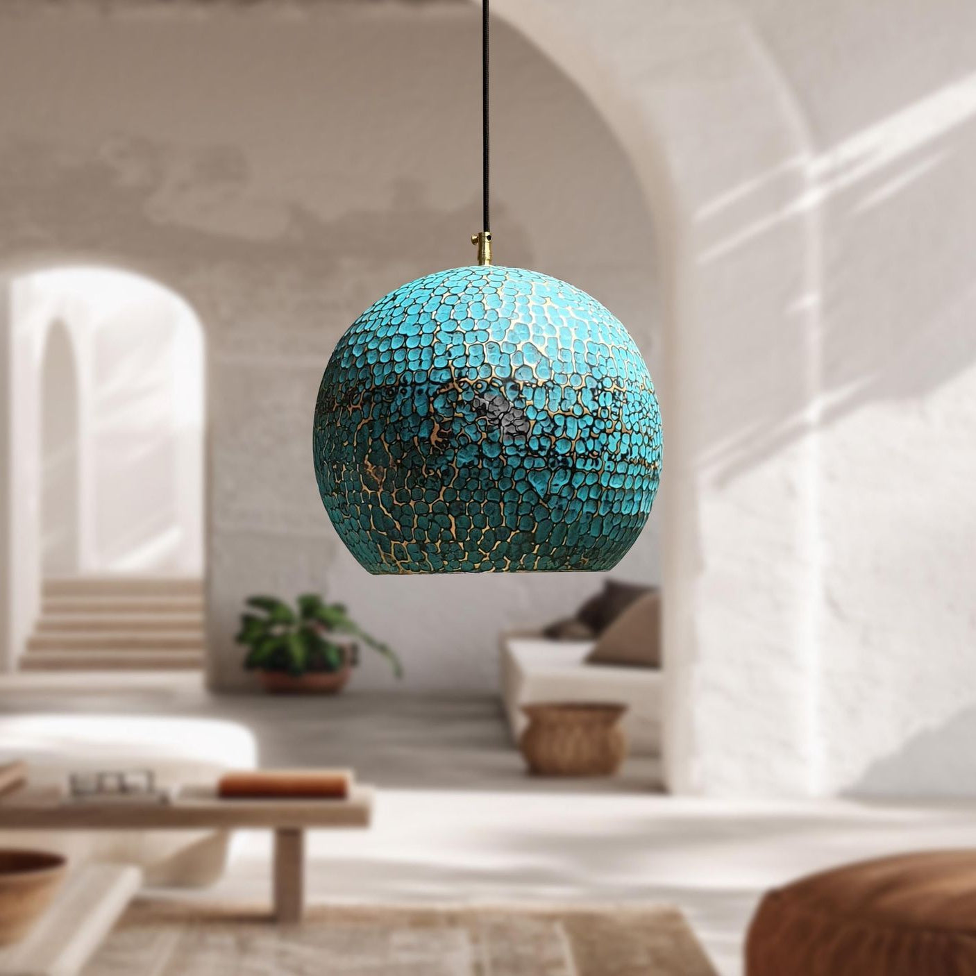 A spherical pendant light with a turquoise blue and gold mosaic tile pattern hanging in a bright, modern living room with white plaster walls and arches.