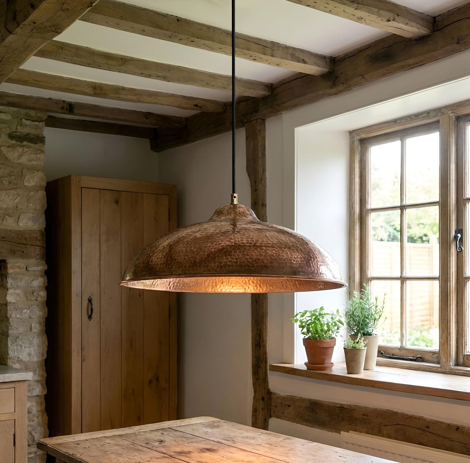 Rustic pendant light hanging in a room with wooden beams and a window.