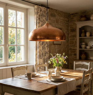 Dining room with wooden table, chairs, and a copper pendant light.