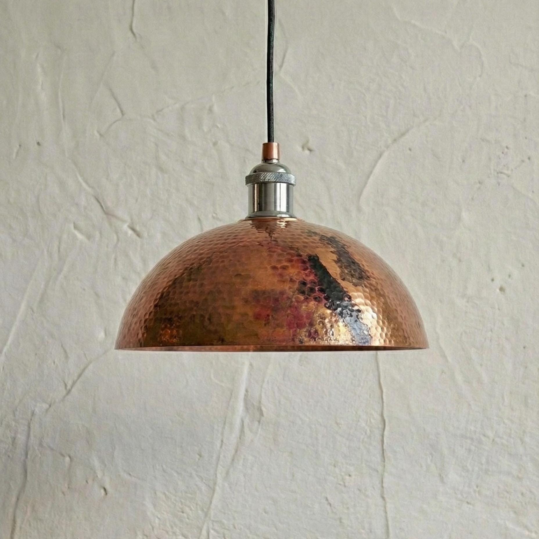 Copper pendant light hanging against a textured beige wall