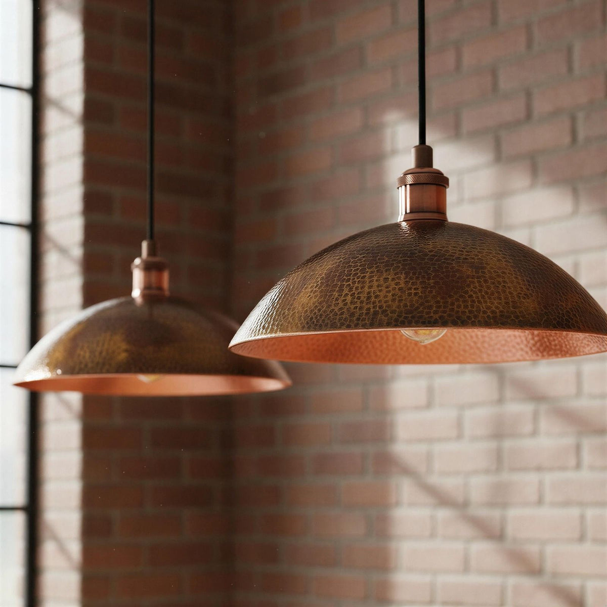 Two copper pendant lights hanging against a brick wall.