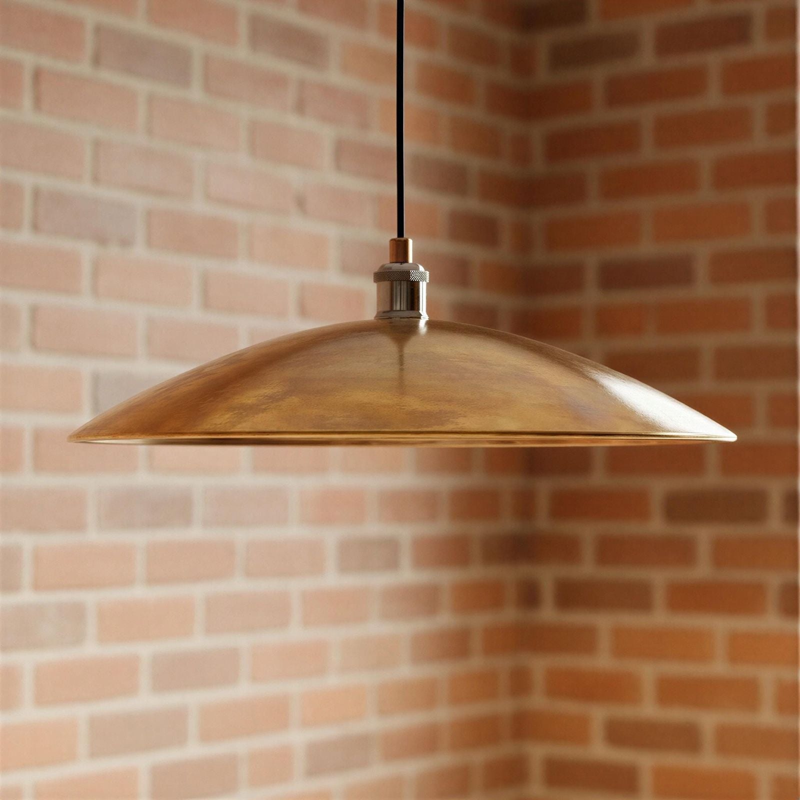 Bronze pendant light hanging against a brick wall